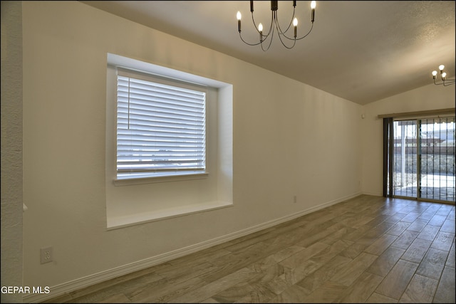 spare room featuring vaulted ceiling, a chandelier, and hardwood / wood-style flooring