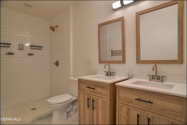 bathroom featuring a tile shower, vanity, and toilet