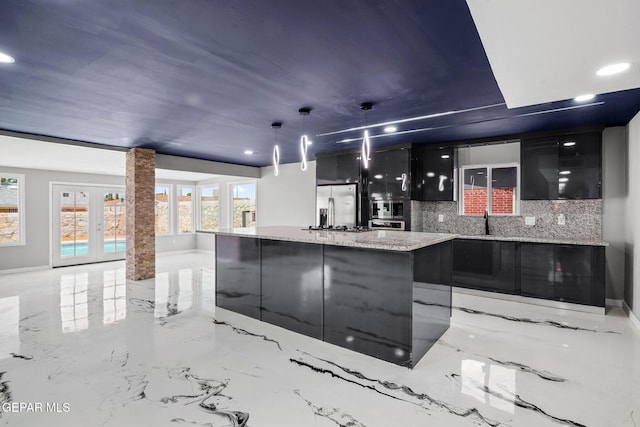 interior space with a center island, ornate columns, backsplash, hanging light fixtures, and stainless steel fridge