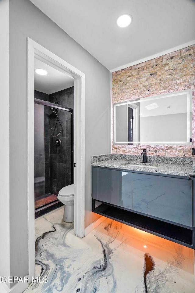 bathroom with a shower with shower door, vanity, and toilet