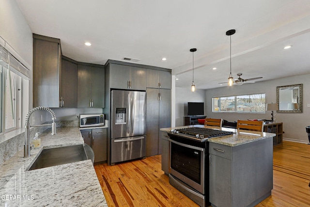 kitchen featuring light stone counters, stainless steel appliances, gray cabinetry, and sink