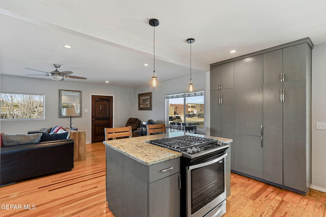 kitchen with stainless steel gas stove, gray cabinetry, a wealth of natural light, and hanging light fixtures