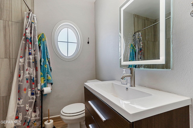 bathroom featuring wood-type flooring, a shower with shower curtain, vanity, and toilet