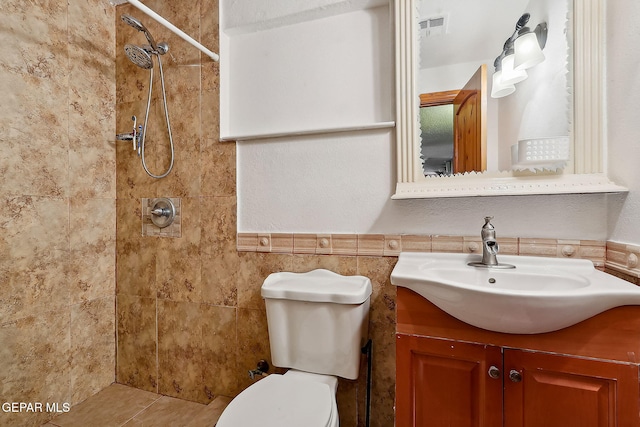 bathroom with toilet, vanity, tile walls, and tiled shower