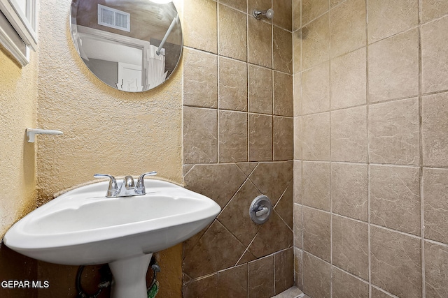 bathroom featuring a tile shower and sink