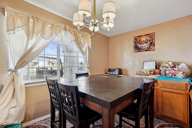 dining space with a textured ceiling and a notable chandelier