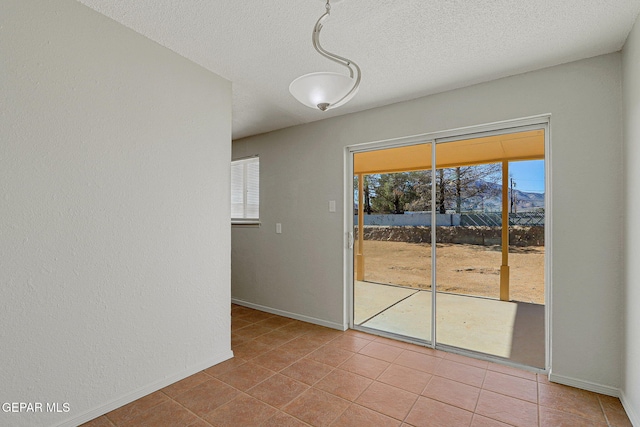 tiled empty room featuring a textured ceiling