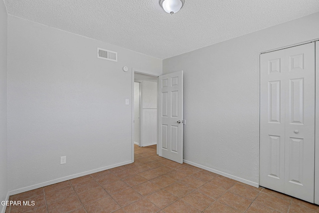 unfurnished bedroom with a textured ceiling, a closet, and light tile patterned floors