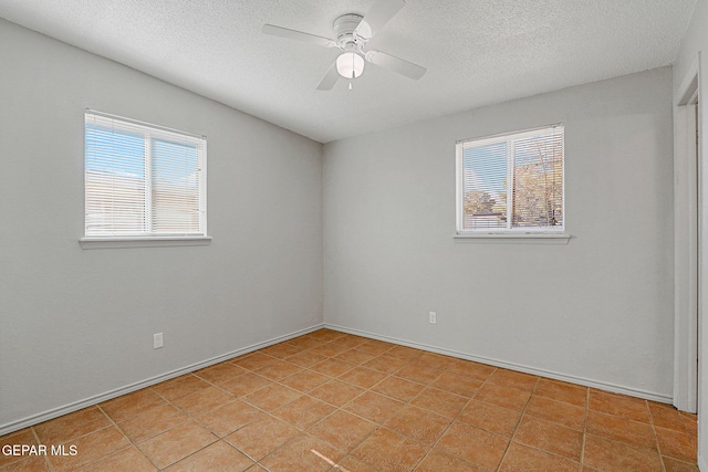 tiled spare room with a textured ceiling, ceiling fan, and plenty of natural light