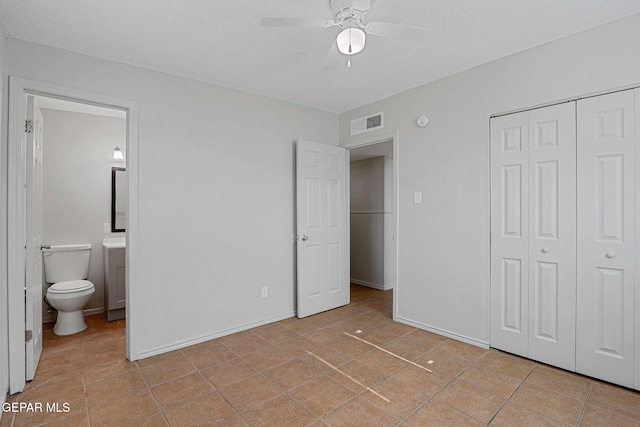 bedroom featuring a textured ceiling, a closet, light tile patterned floors, connected bathroom, and ceiling fan