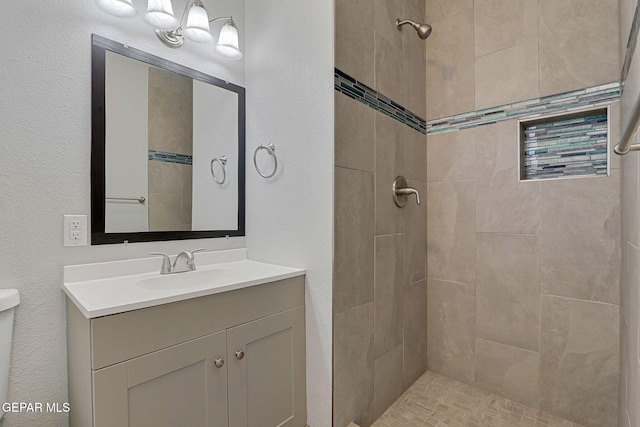 bathroom featuring tiled shower, vanity, and toilet