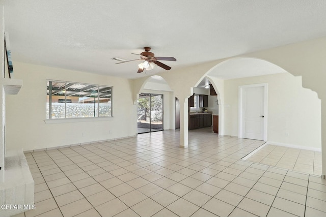 tiled empty room featuring ceiling fan and a textured ceiling