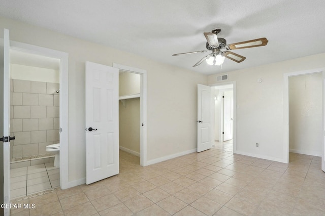 unfurnished bedroom with ensuite bathroom, ceiling fan, a textured ceiling, light tile patterned floors, and a closet