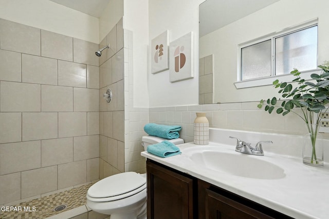 bathroom with toilet, vanity, tile walls, and tiled shower