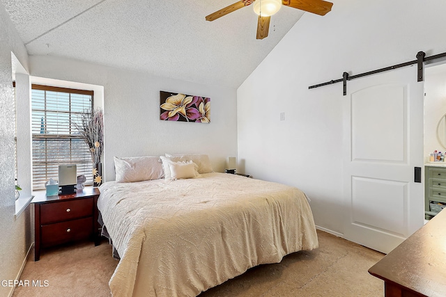 bedroom with a textured ceiling, vaulted ceiling, ceiling fan, a barn door, and light colored carpet