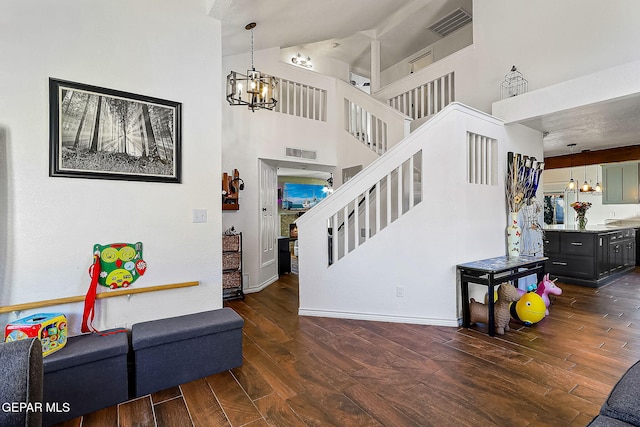 stairs with a towering ceiling, hardwood / wood-style flooring, and a notable chandelier