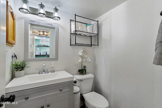 bathroom featuring a textured ceiling, vanity, and toilet