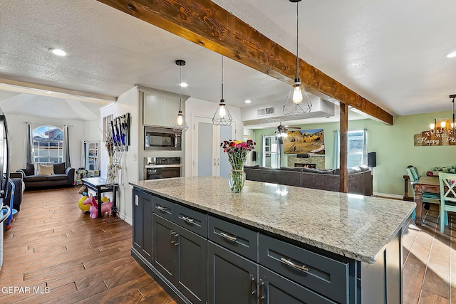 kitchen featuring stainless steel appliances, decorative light fixtures, a textured ceiling, beamed ceiling, and a kitchen island