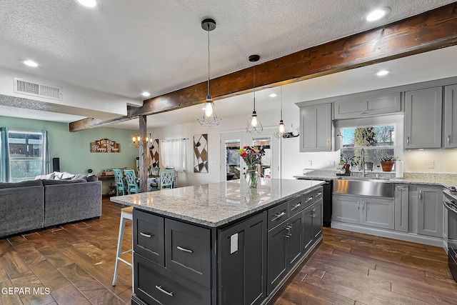 kitchen featuring sink, a center island, pendant lighting, and beamed ceiling