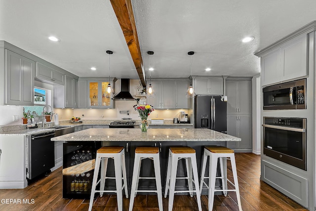 kitchen featuring light stone countertops, a center island, wall chimney range hood, black appliances, and beamed ceiling