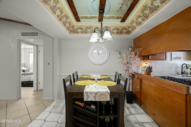 tiled dining space featuring ornamental molding, a notable chandelier, sink, and a tray ceiling