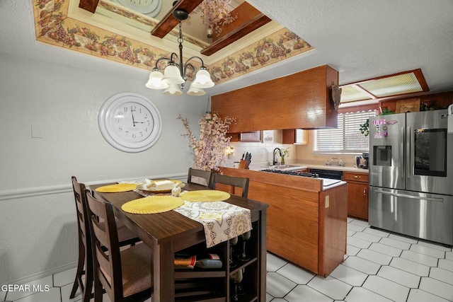 dining area featuring a raised ceiling, a chandelier, and sink