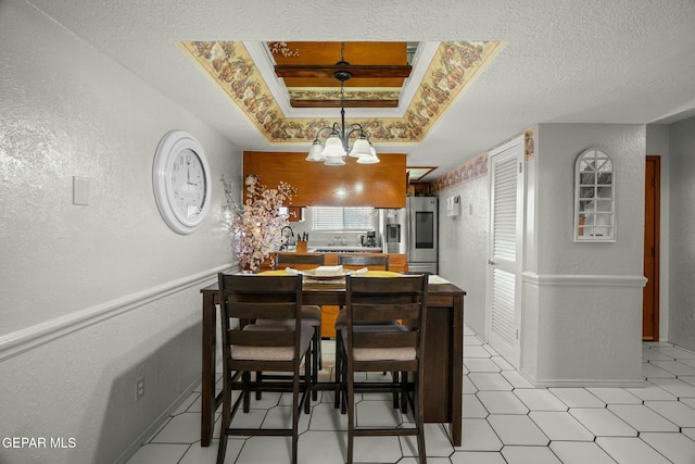 dining area with a chandelier, a tray ceiling, and ornamental molding