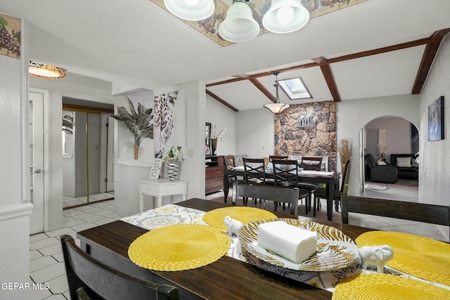 dining room featuring a textured ceiling, a skylight, and light tile patterned floors