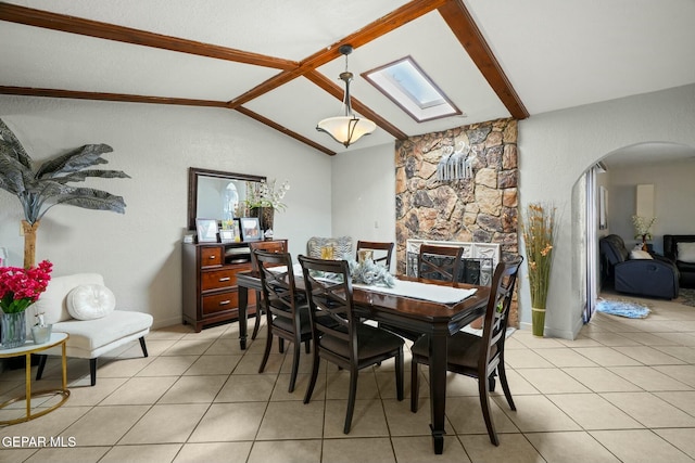 tiled dining room featuring lofted ceiling with skylight