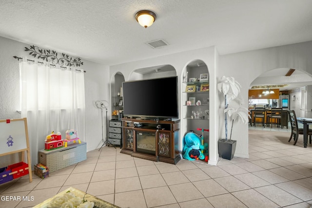 tiled living room featuring a textured ceiling and built in shelves