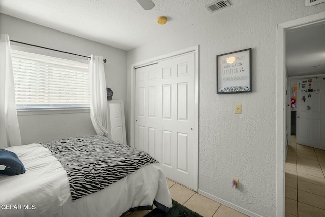 bedroom featuring ceiling fan, a closet, and light tile patterned floors