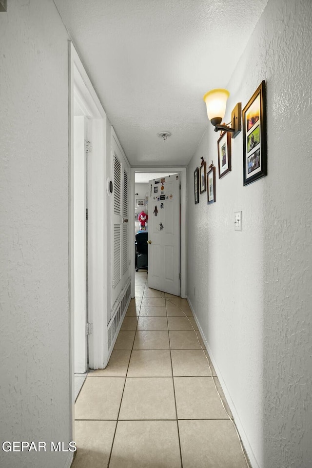 hall featuring a textured ceiling and light tile patterned floors