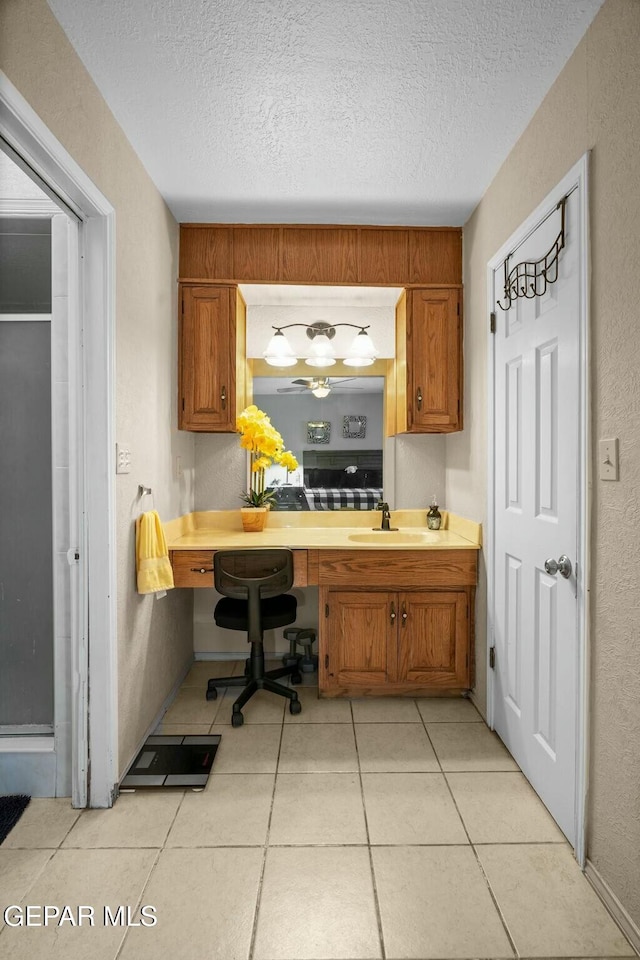 kitchen with a textured ceiling, light tile patterned floors, and sink