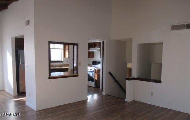 empty room featuring dark wood-type flooring and a high ceiling