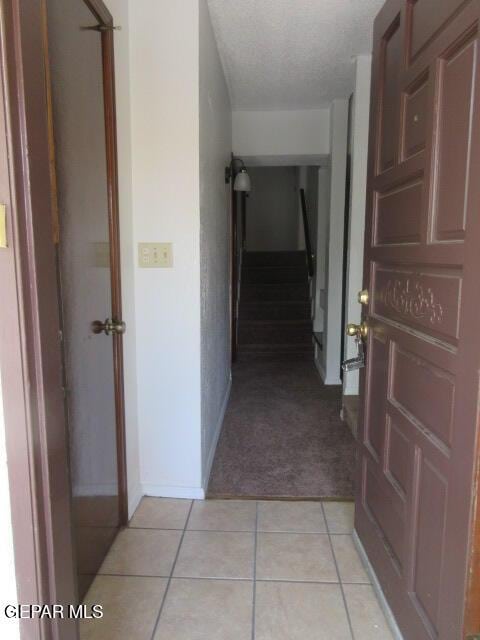 corridor featuring a textured ceiling and light tile patterned flooring