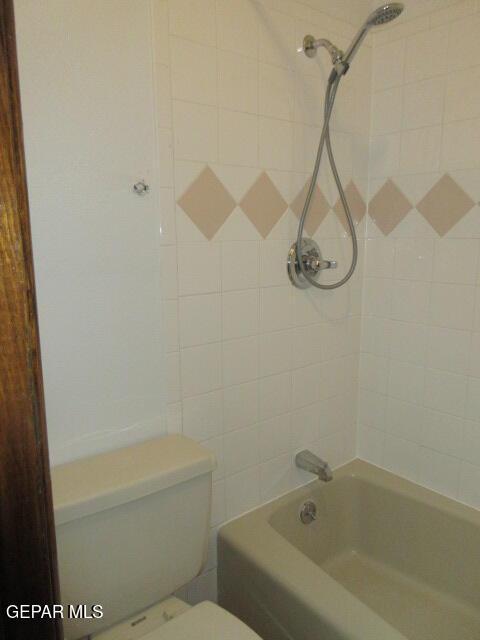 bathroom with toilet and tiled shower / bath