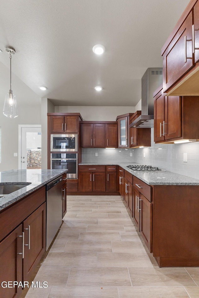 kitchen with glass insert cabinets, light stone countertops, appliances with stainless steel finishes, and wall chimney range hood