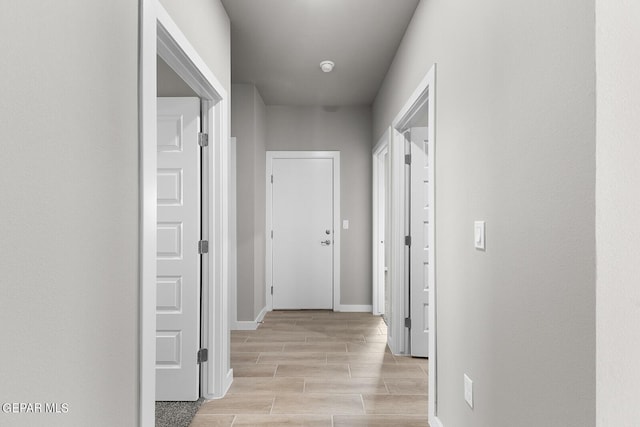 hall featuring baseboards and wood tiled floor