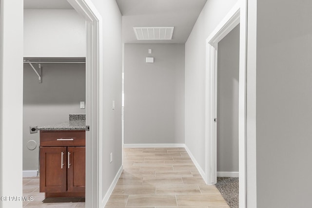 hall featuring baseboards, visible vents, and wood finish floors