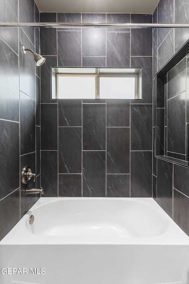 bathroom featuring a healthy amount of sunlight and tiled shower / bath