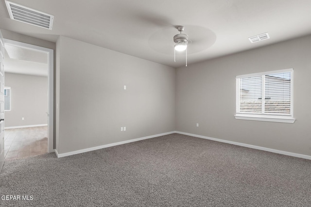 unfurnished room with carpet floors, visible vents, baseboards, and a ceiling fan