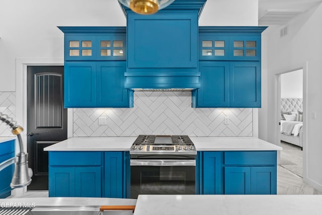 kitchen featuring blue cabinetry, backsplash, and stainless steel gas range