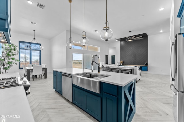 kitchen with a center island with sink, appliances with stainless steel finishes, hanging light fixtures, light parquet floors, and ceiling fan