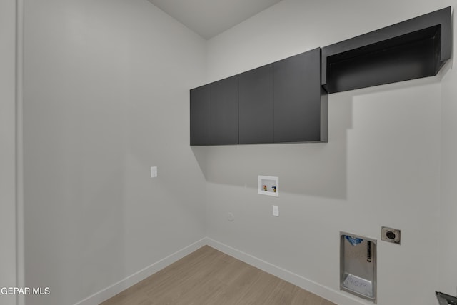 12869 Kingsbury Ave, Horizon City, TX 79928 - laundry room with hookup for a washing machine, light wood-style flooring, electric dryer hookup, cabinet space, and baseboards