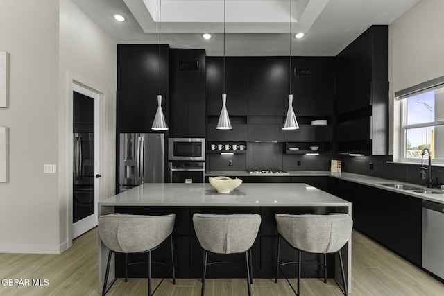 12869 Kingsbury Ave, Horizon City, TX 79928 - kitchen with modern cabinets, dark cabinets, appliances with stainless steel finishes, light wood finished floors, and recessed lighting