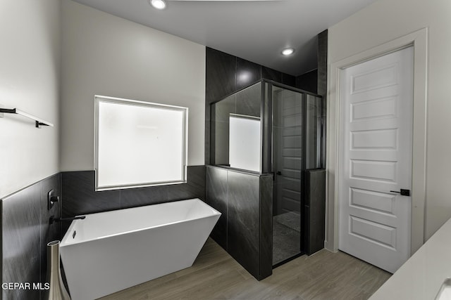 12869 Kingsbury Ave, Horizon City, TX 79928 - bathroom featuring a soaking tub, a stall shower, wood finished floors, tile walls, and recessed lighting