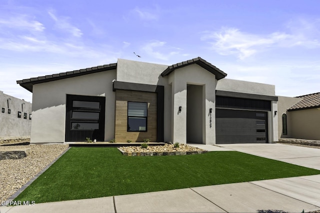 12869 Kingsbury Ave, Horizon City, TX 79928 - modern home with an attached garage, concrete driveway, a front lawn, and stucco siding
