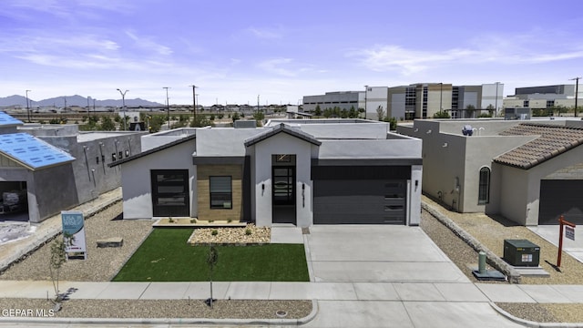 12869 Kingsbury Ave, Horizon City, TX 79928 - contemporary house with stucco siding, concrete driveway, a mountain view, and an attached garage