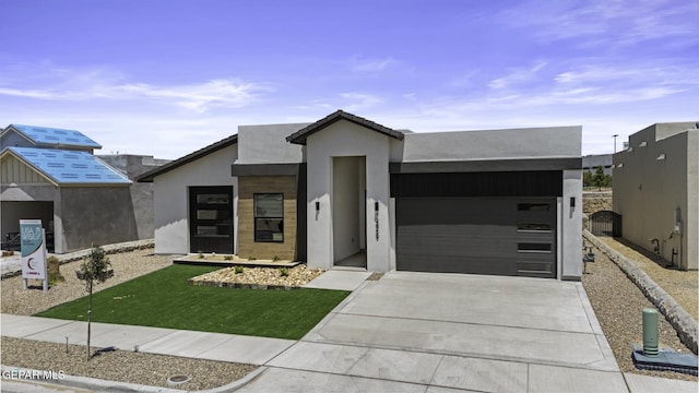 12869 Kingsbury Ave, Horizon City, TX 79928 - view of front of property featuring an attached garage, driveway, stucco siding, and a front yard