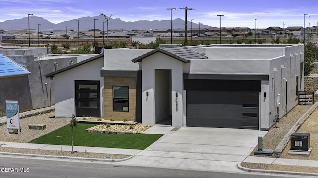 12869 Kingsbury Ave, Horizon City, TX 79928 - modern home with stucco siding, a garage, a mountain view, and driveway